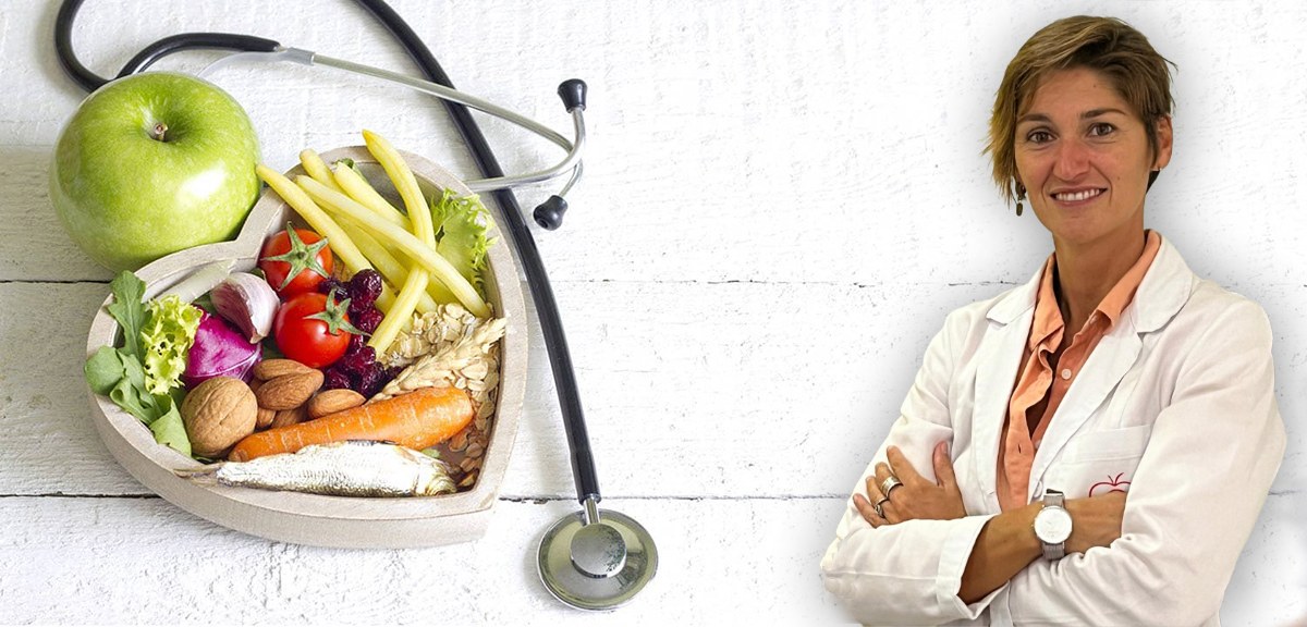 Giorgia Saccone in camice, accanto a frutta, verdura e alimenti per una nutrizione equilibrata